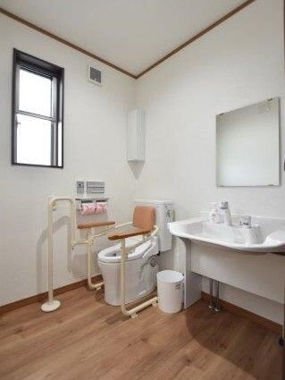 背もたれと手すりが付いたトイレのそばにはゴミ箱が置かれ、車いす対応の洗面所も付いている。