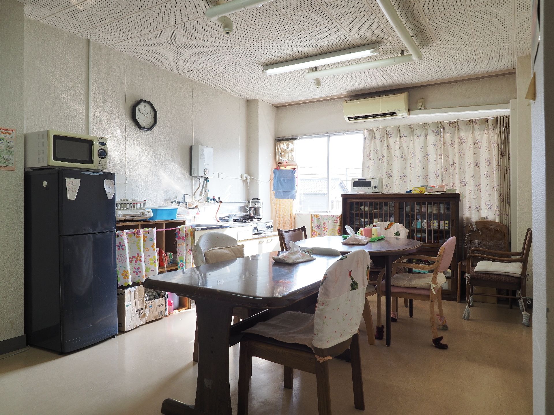 冷蔵庫やキッチンがあり、中央にテーブルと椅子がある食堂