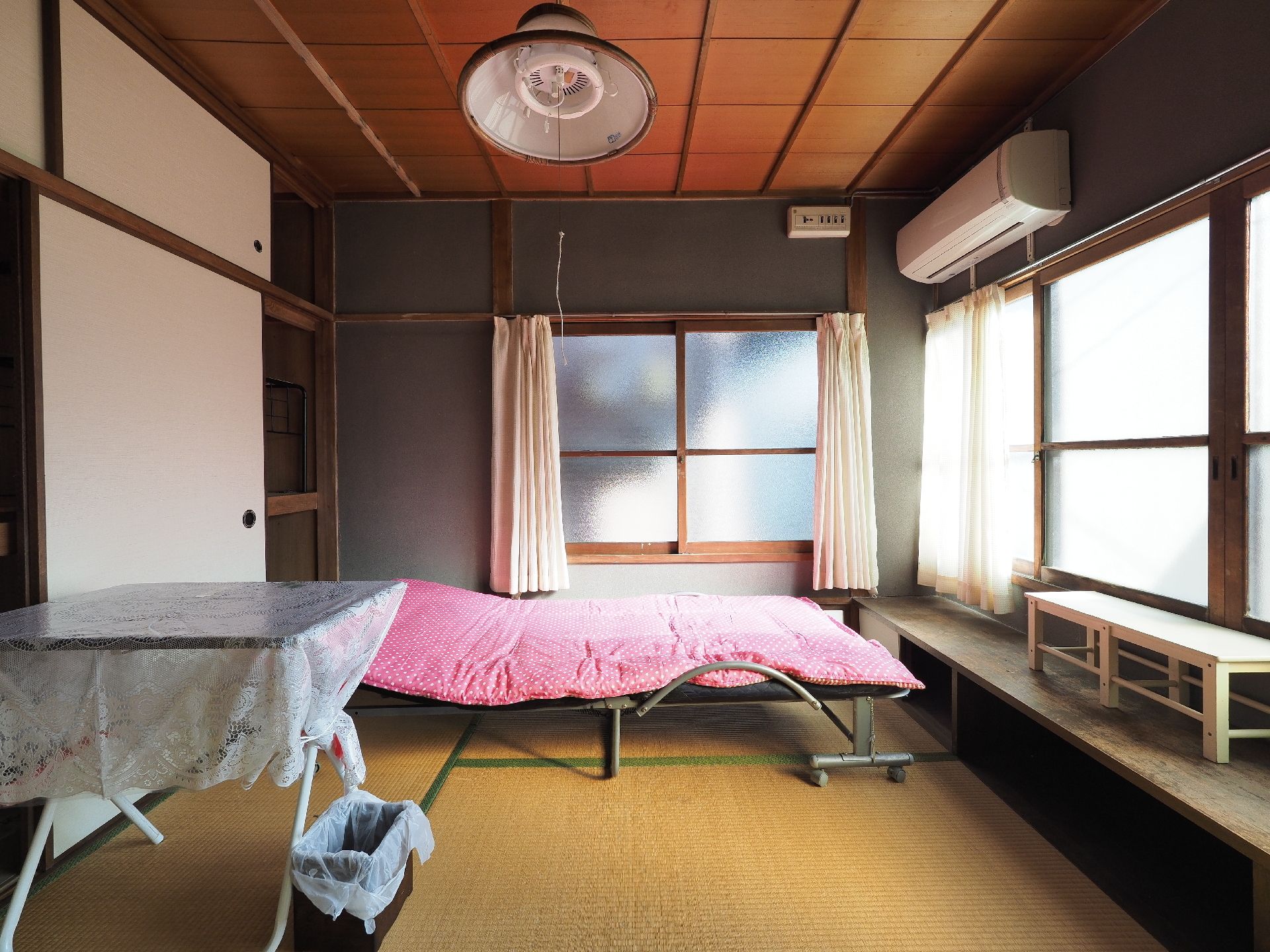 畳で押し入れがある部屋にベッドとテーブルが置かれた和室