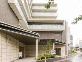 アスファルトに隣接したベージュの外観で側面にガラスが付いている建物