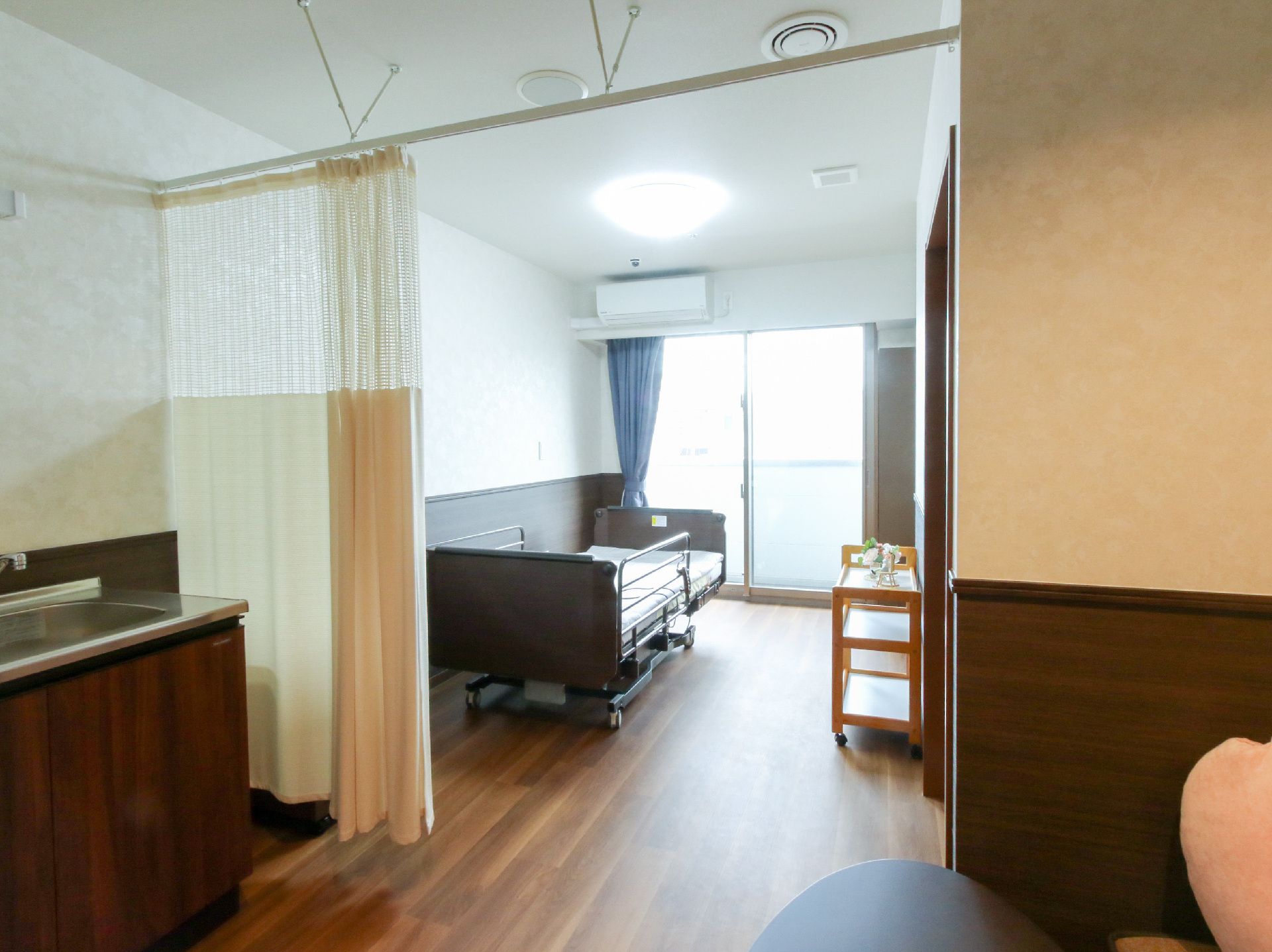 窓から日差しが入り、介護ベッドが置かれている居室