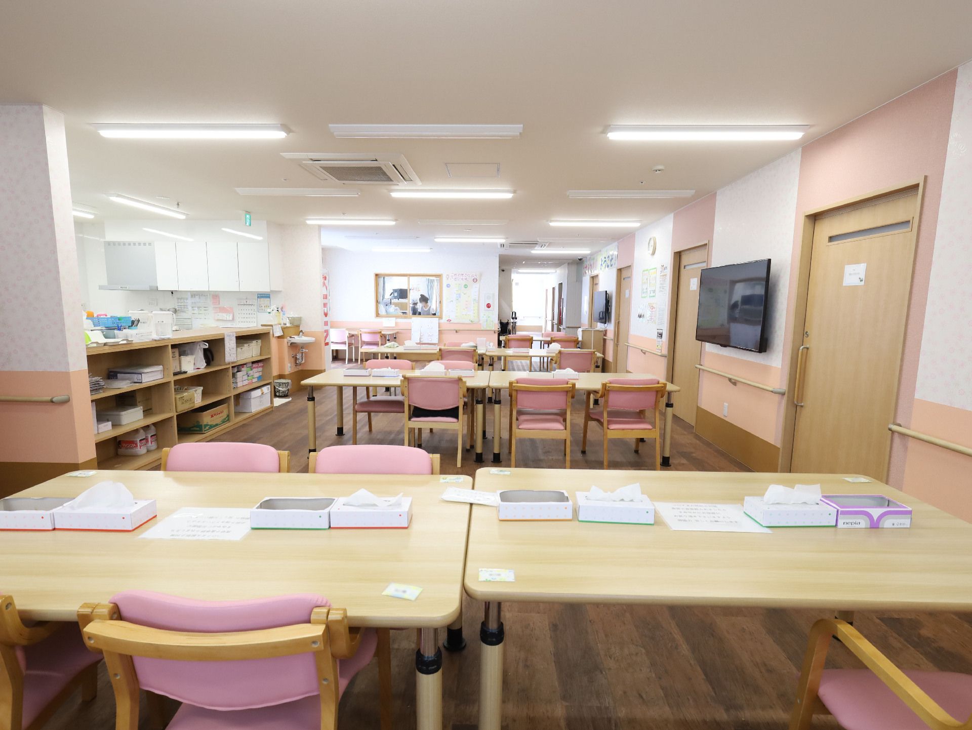 木製の机とピンクのクッションがついた木製の椅子が置かれた白い壁の部屋