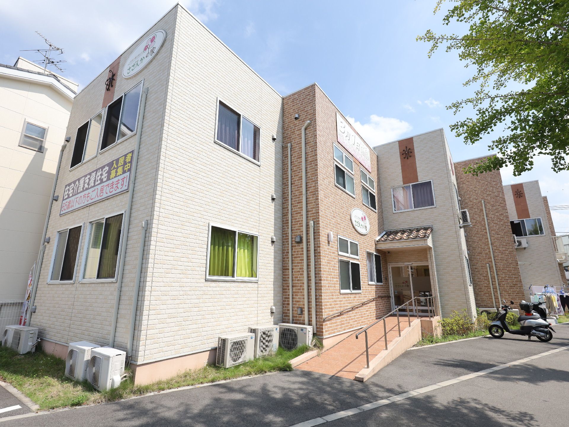 アスファルトの道路沿いに立地している白とレンガ調の外観の建物