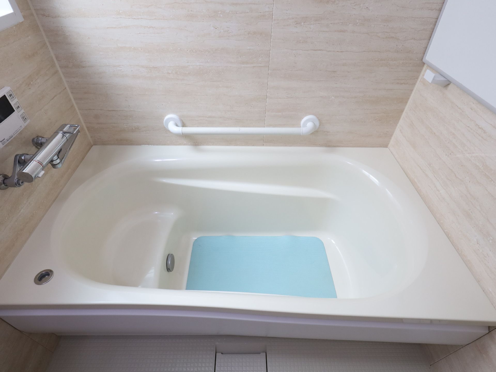 白い壁の浴室に配置された青いマットレスが敷かれた白い浴槽