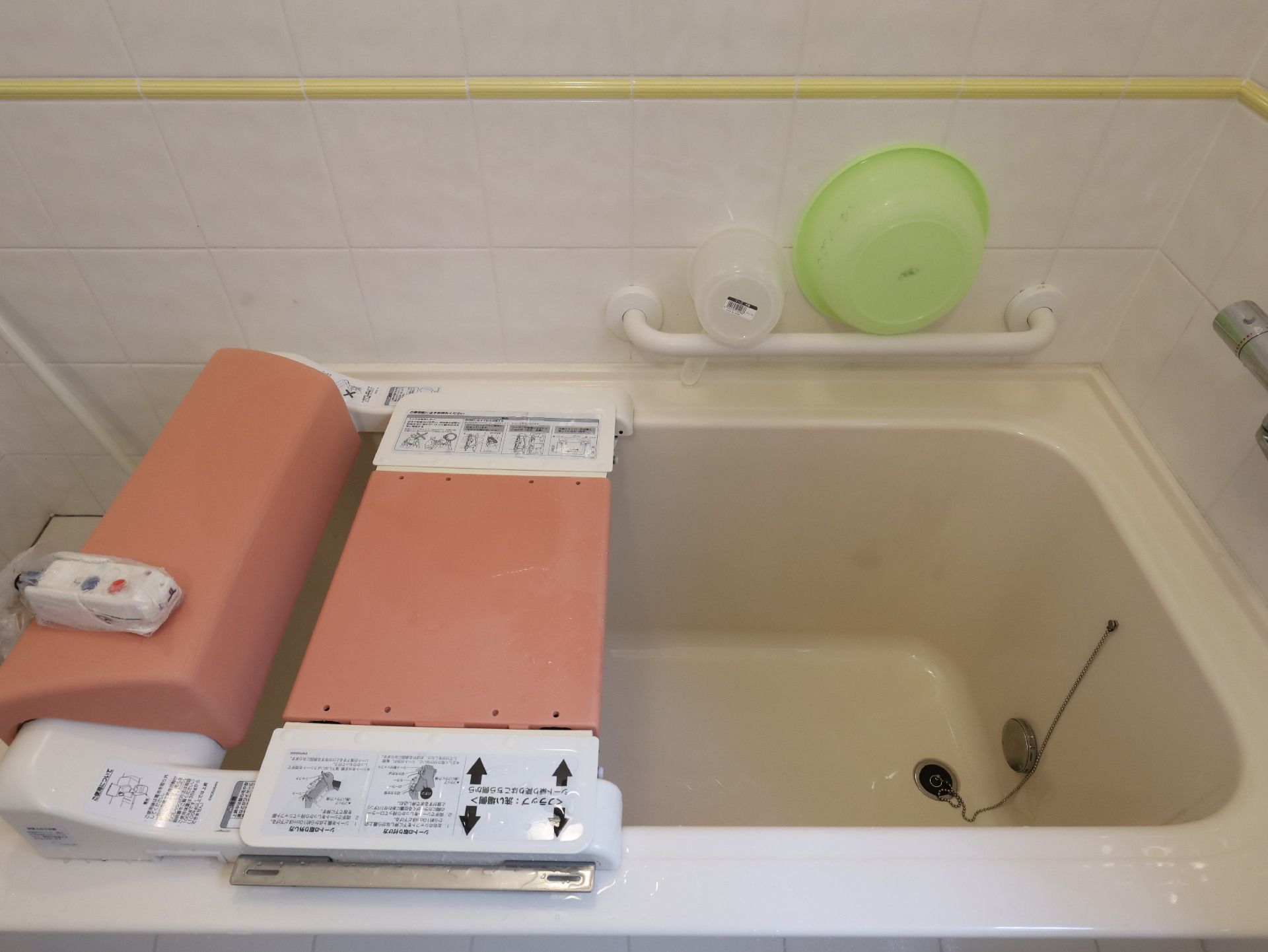 白い壁の部屋に置かれた浴槽についているピンクのリフト