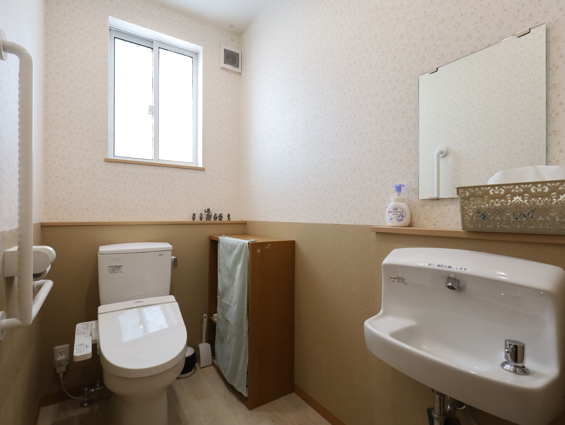 洗面台と洋式便器が置かれた手すりが付いている白い壁の部屋