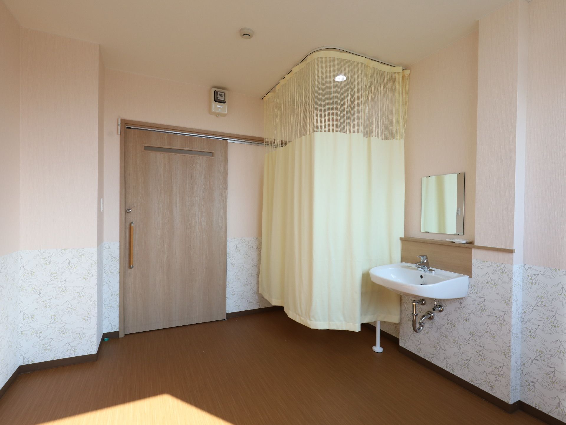 カーテンで一角が仕切られた白い壁の部屋