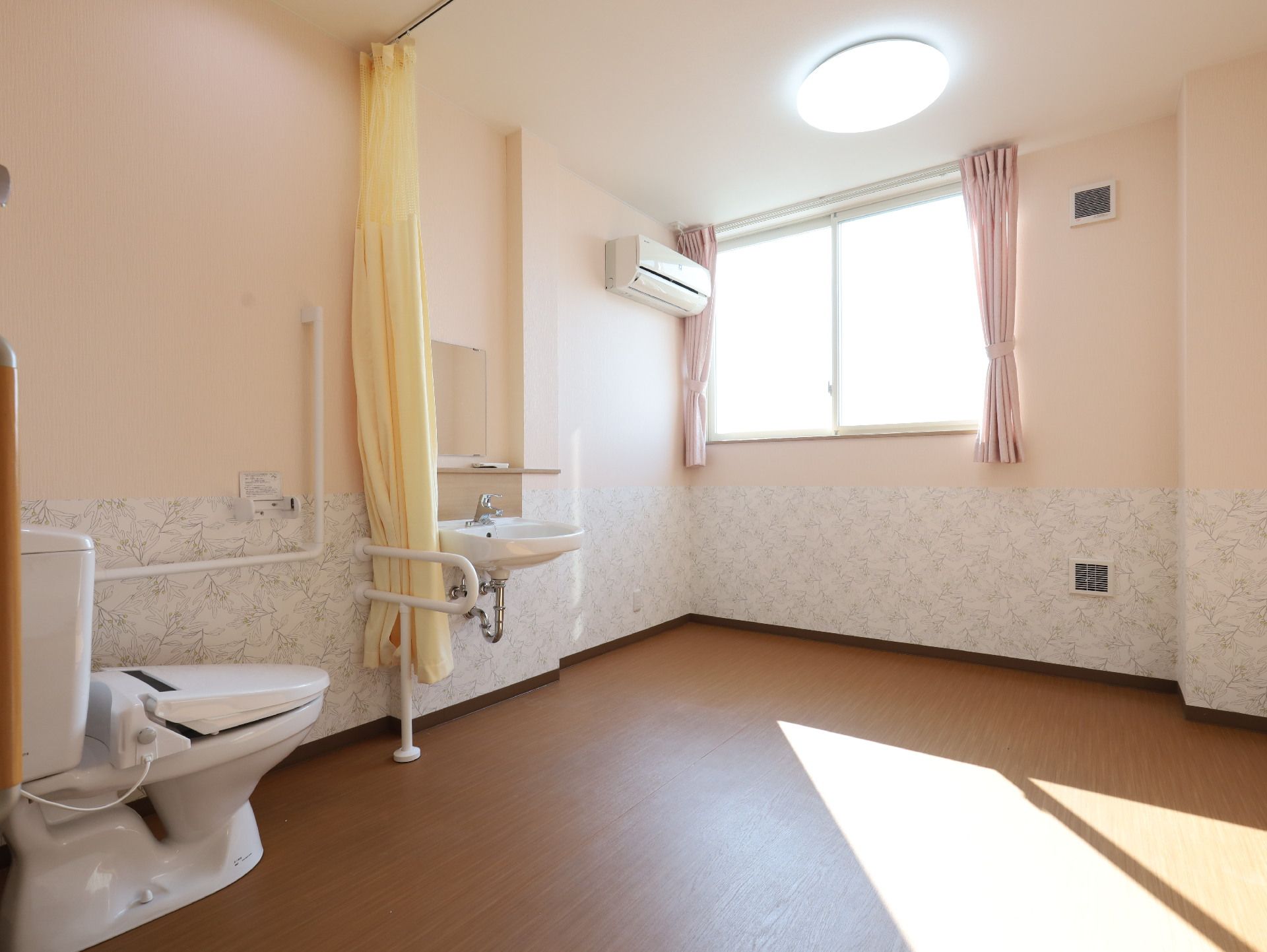 トイレと洗面台とエアコンがある白い壁の部屋