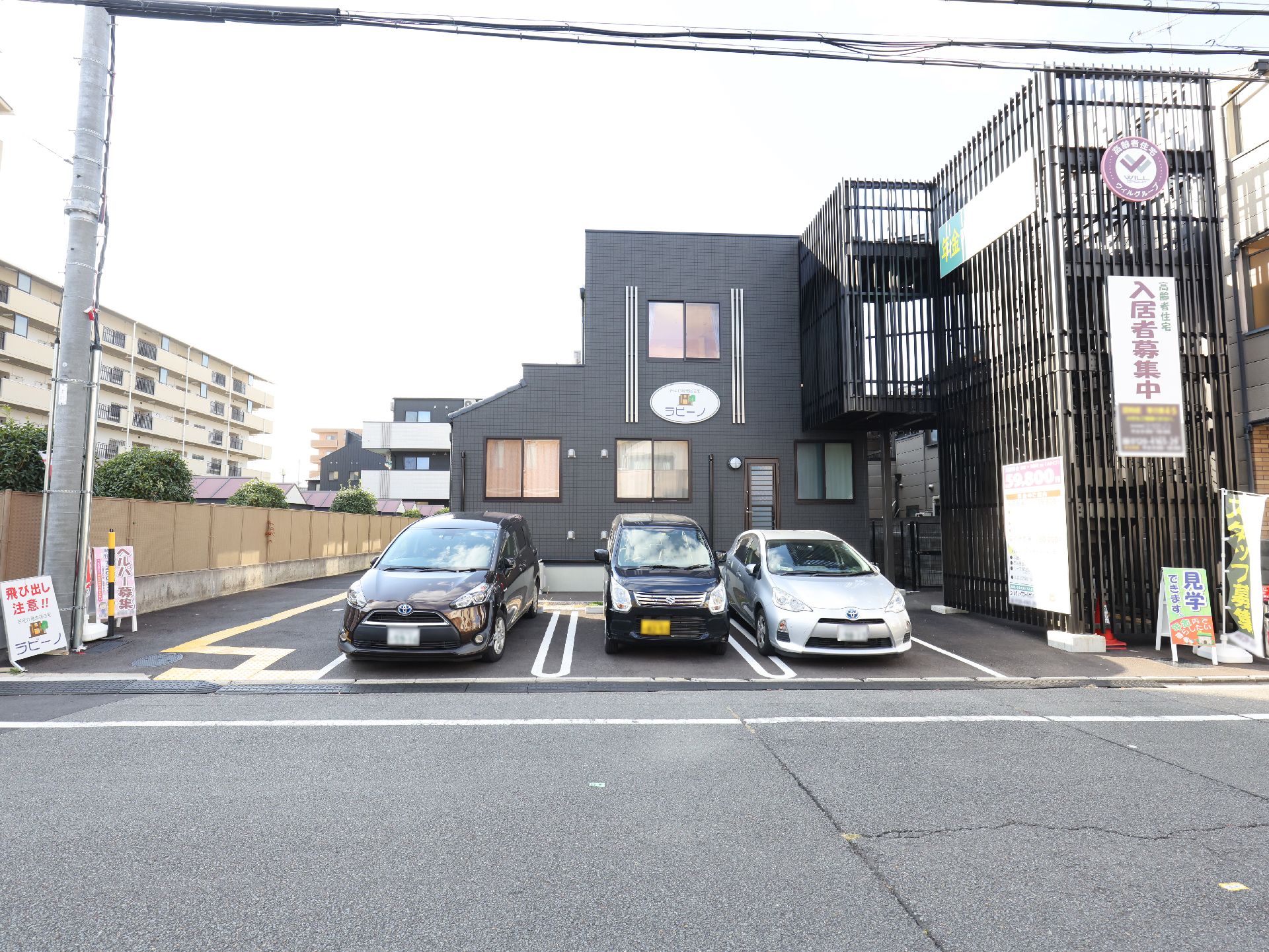 ピンクのエプロンを付けた若い女性スタッフが笑顔で高齢女性に寄り添っている。