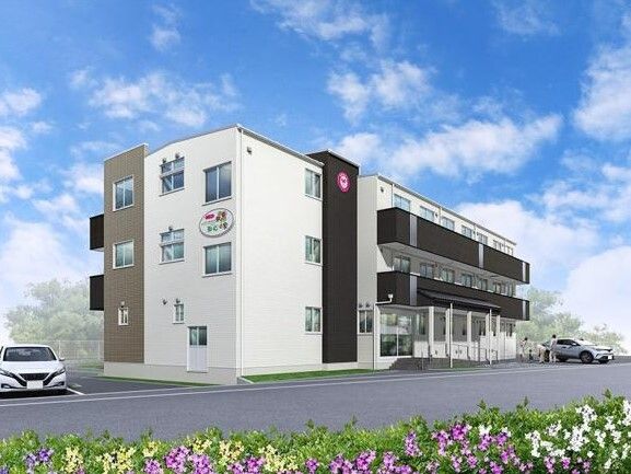 白とダークグレーで敷地内には駐車場があり、各フロアにベランダがある3階建ての建物は日当たりのいい場所に建っている。