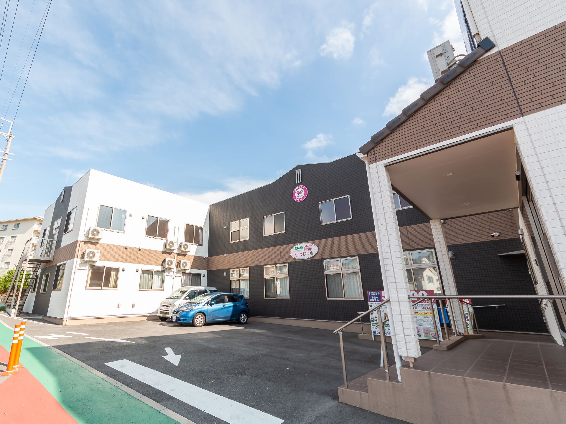 車が止まった駐車場に隣接しているコの字型で白と黒の外観の建物