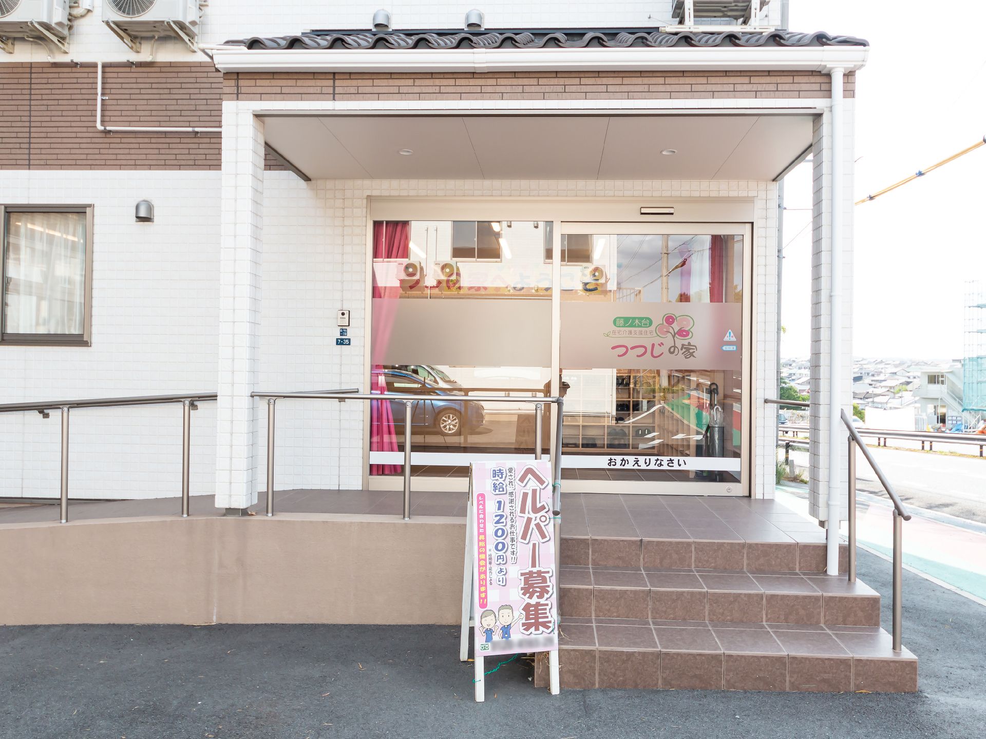 白い壁の建物の入り口に配置された手すりが付いた階段とスロープ