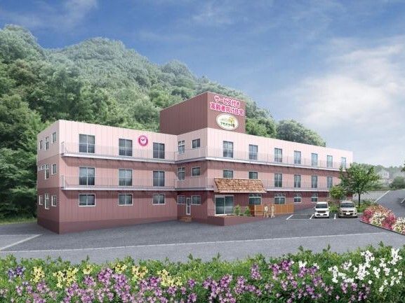 3階建ての建物はピンク系のグラデーションとなっていて、建物の後ろには森のような場所がある。