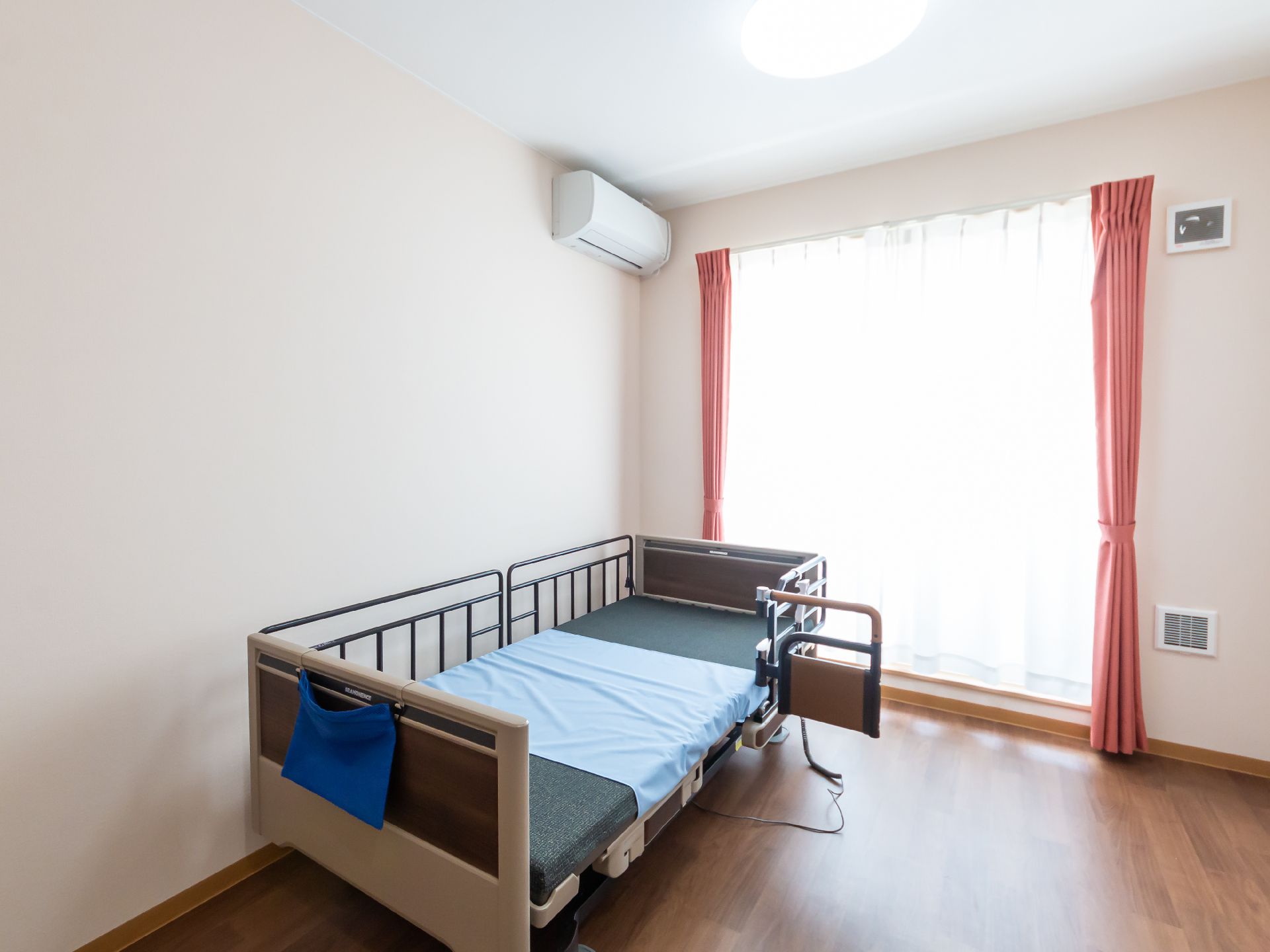 青いマットが敷かれたベッドのある白い壁の部屋