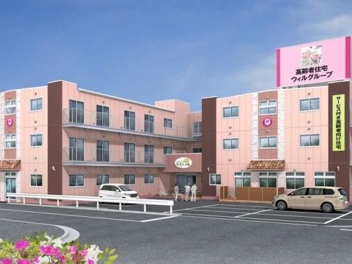 エル字型の３階建ての建物はピンクとブラウンで敷地内には駐車場があり、玄関には手すり付きのスロープがある。