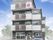 駐車場が付いた３階建ての建物。各フロアにベランダがあり、住宅名やロゴマークが外壁に書かれている。