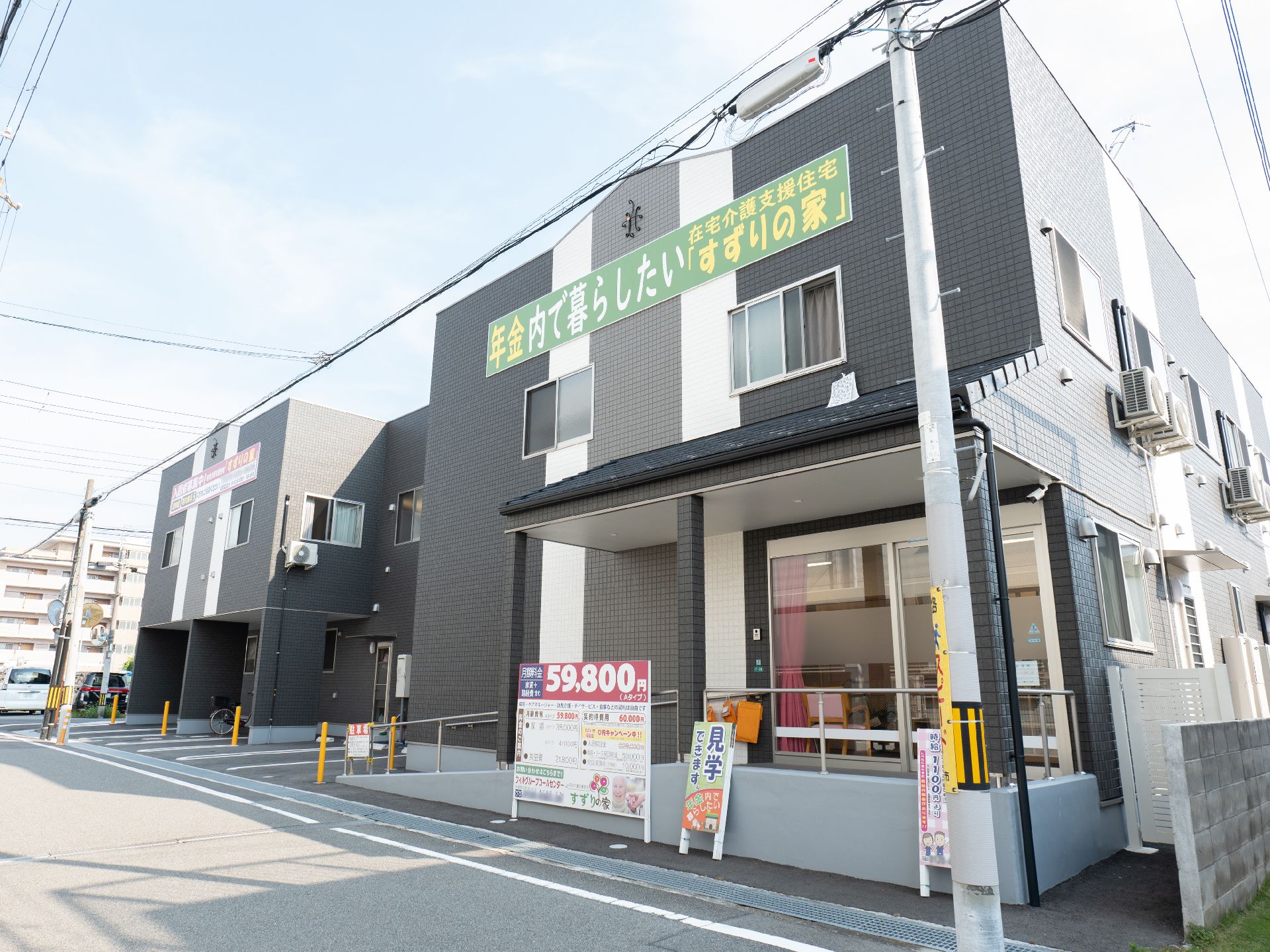 アスファルト沿いに立地している黒い外観で２階建ての建物