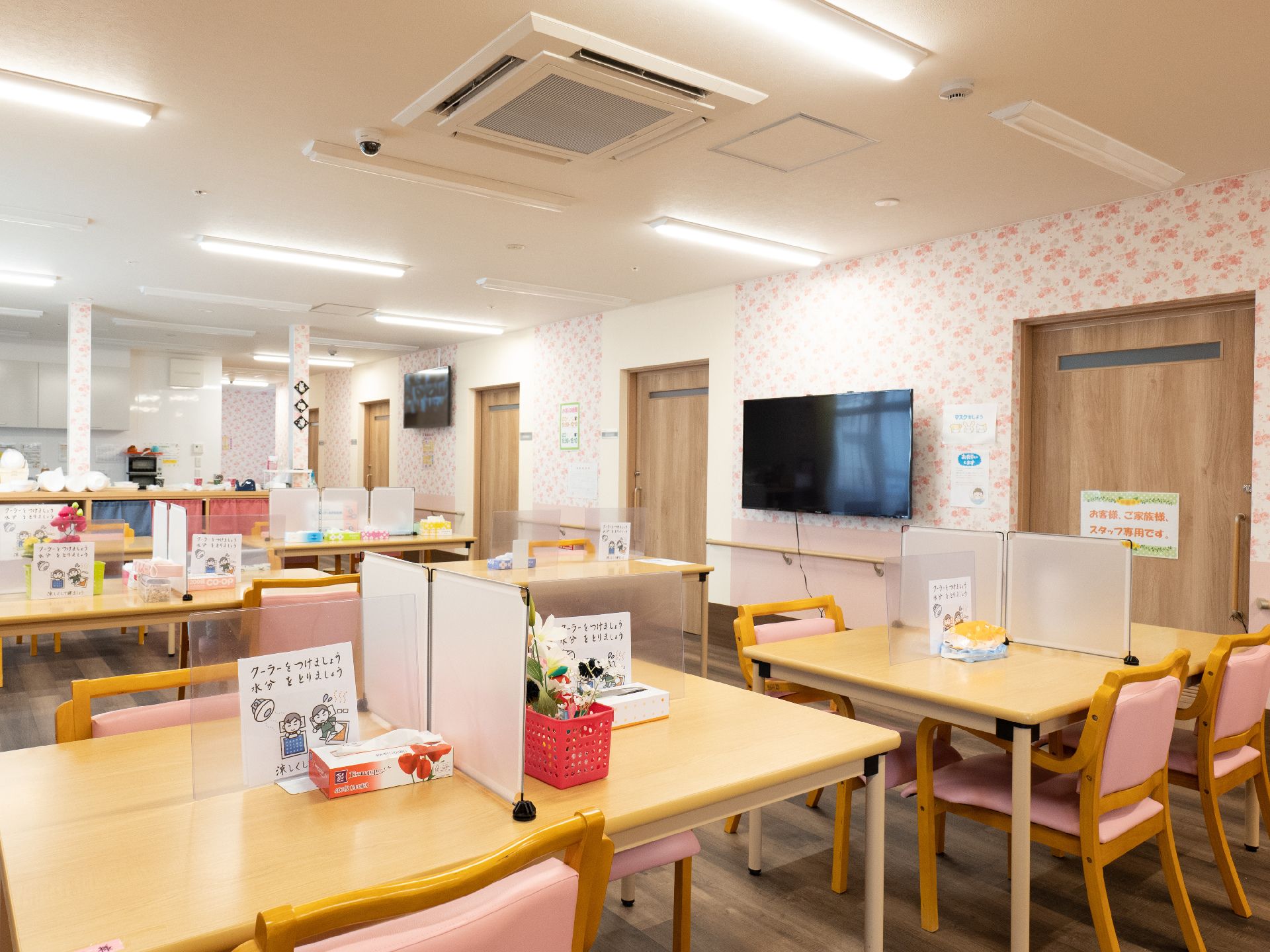 木製の机と椅子が並んでいる白い壁の広間
