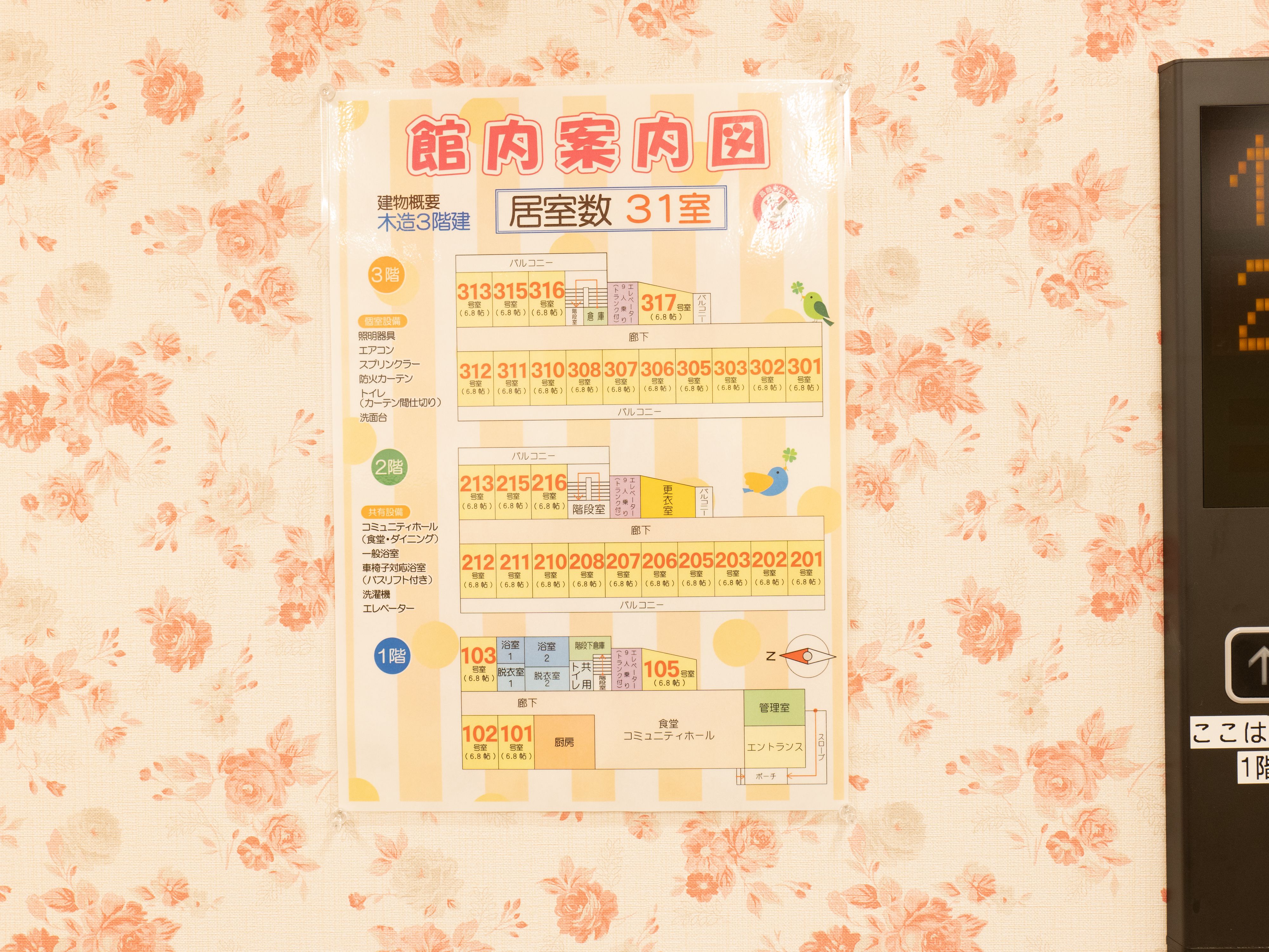 花柄の壁に貼られたラミネート加工されている館内案内図と書かれた紙