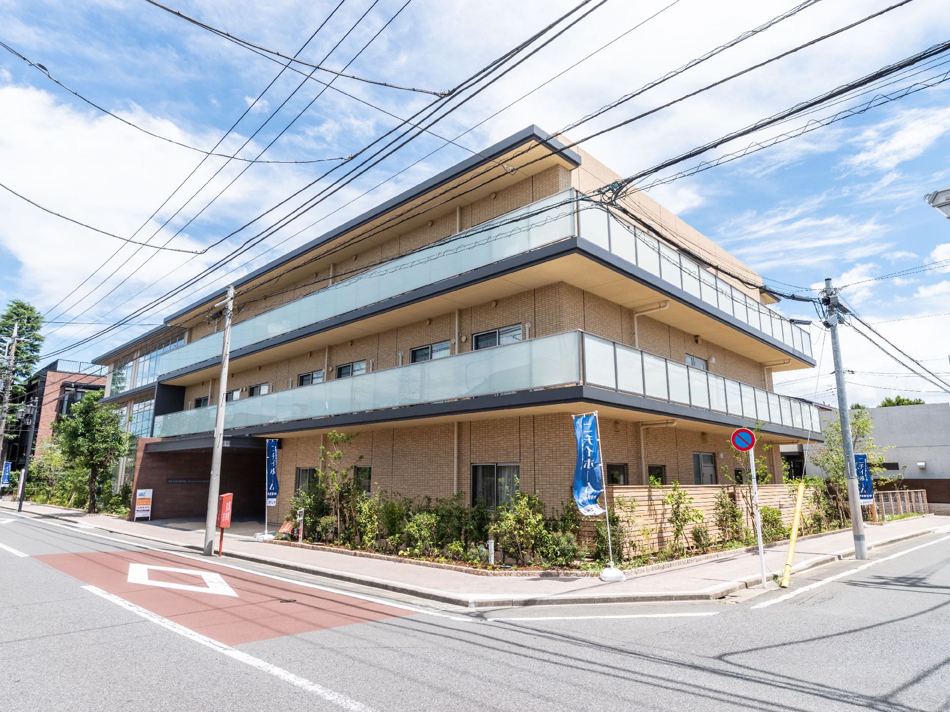 ３階建ての建物はどっしりとした雰囲気で、各フロアにベランダがあり、建物の周りには木や花が植えられている。
