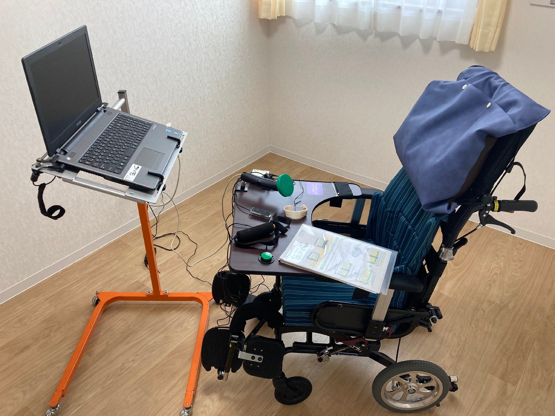 車いすの高齢者と手を握りながら話す介護スタッフの様子。施設内での会話の場面