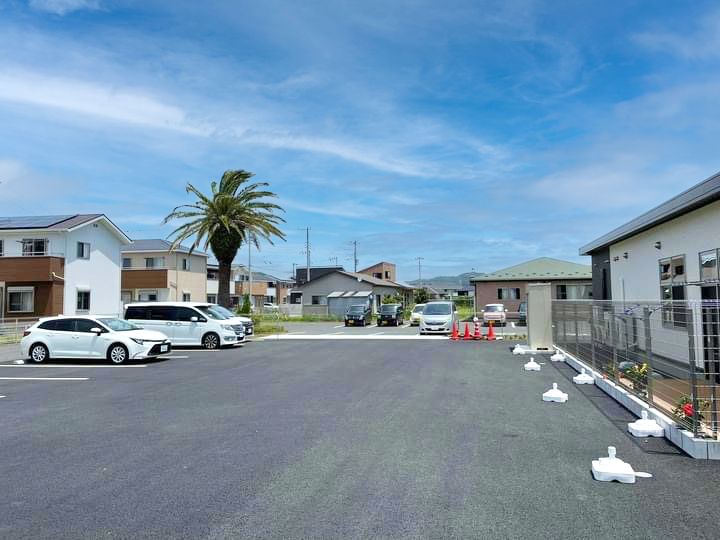 車が数台止まっている駐車場が付いたホーム。周りには背の高い建物がなく、青い空が広がっている。