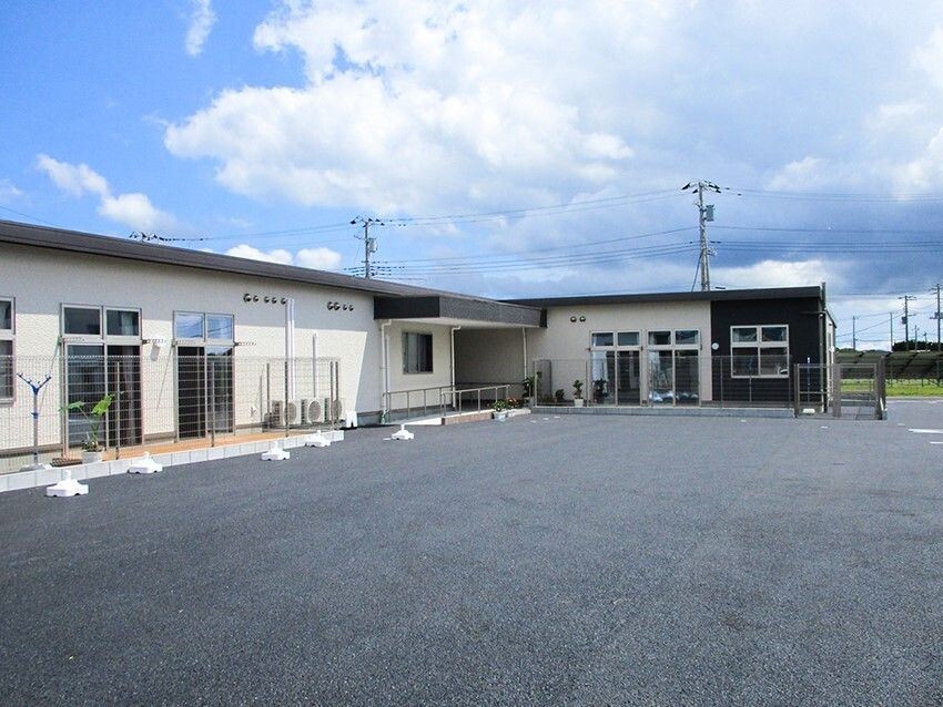 洗濯物干し場がある平屋建ての建物。敷地は広く、駐車場も付いている。
