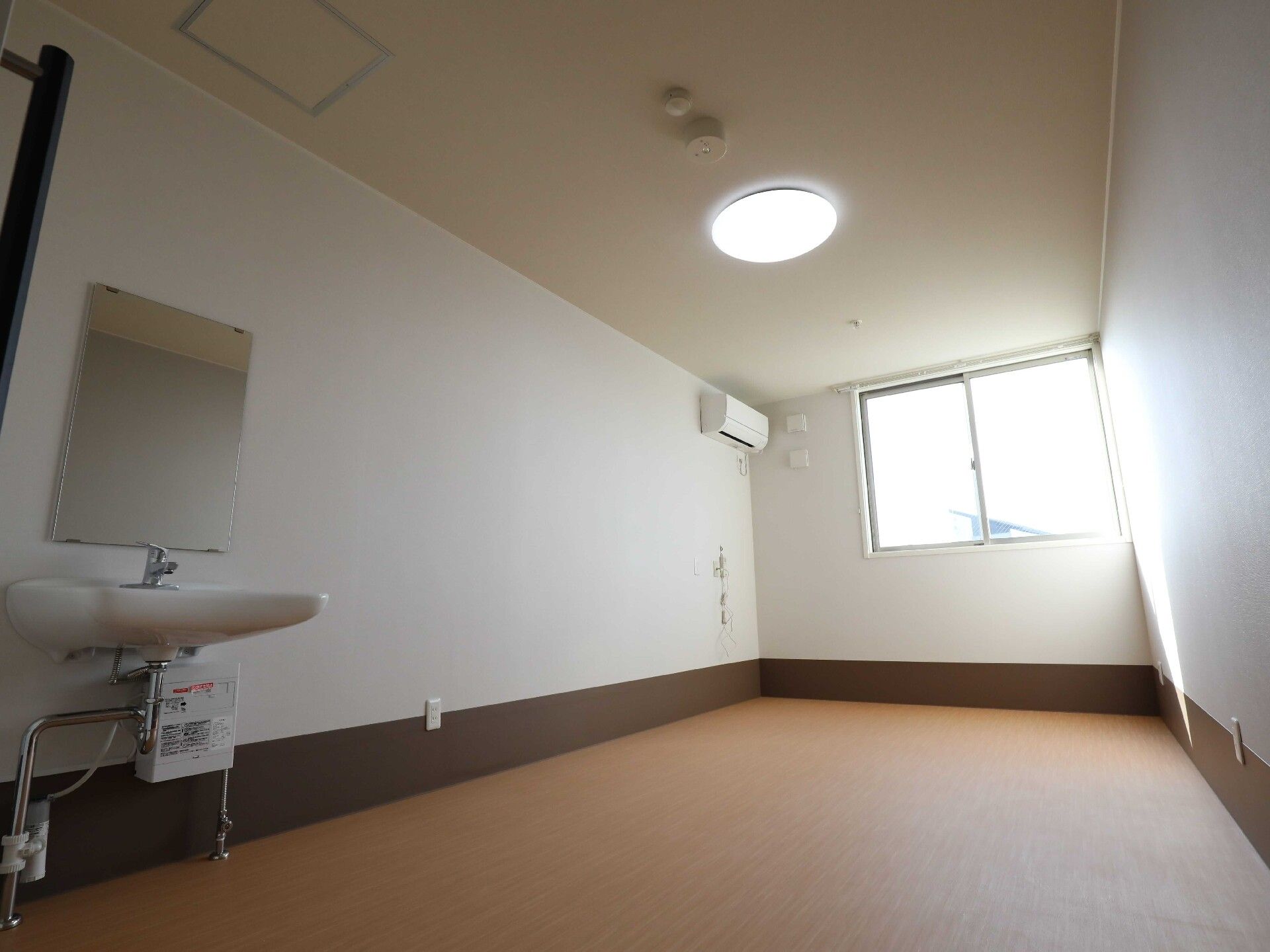 家具や家電は置かれていないシンプルな部屋。エアコンや車いす対応の洗面所がある。