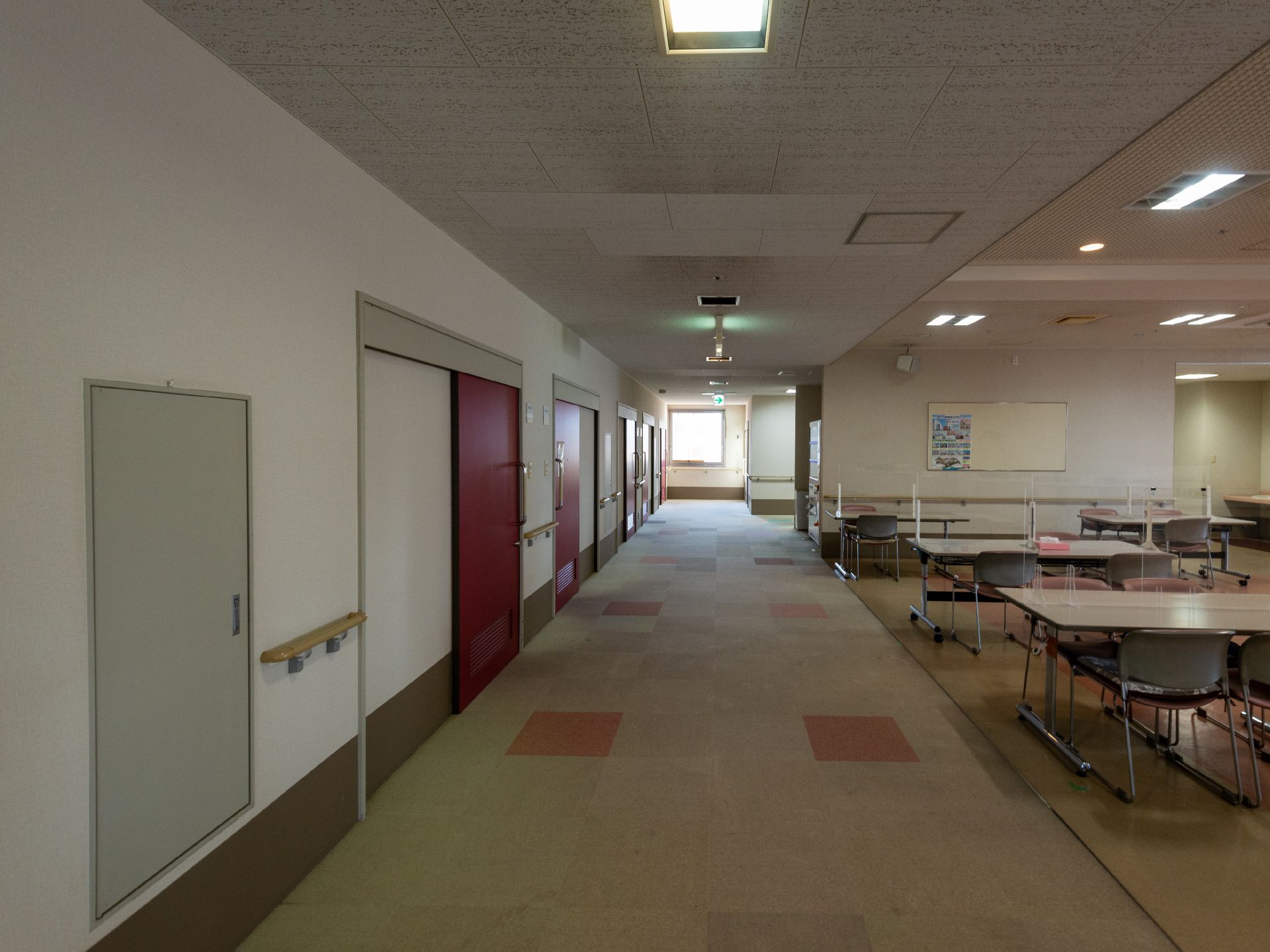 なにかを見て笑顔で手をたたいている高齢女性とスタッフの様子。施設での一場面の写真