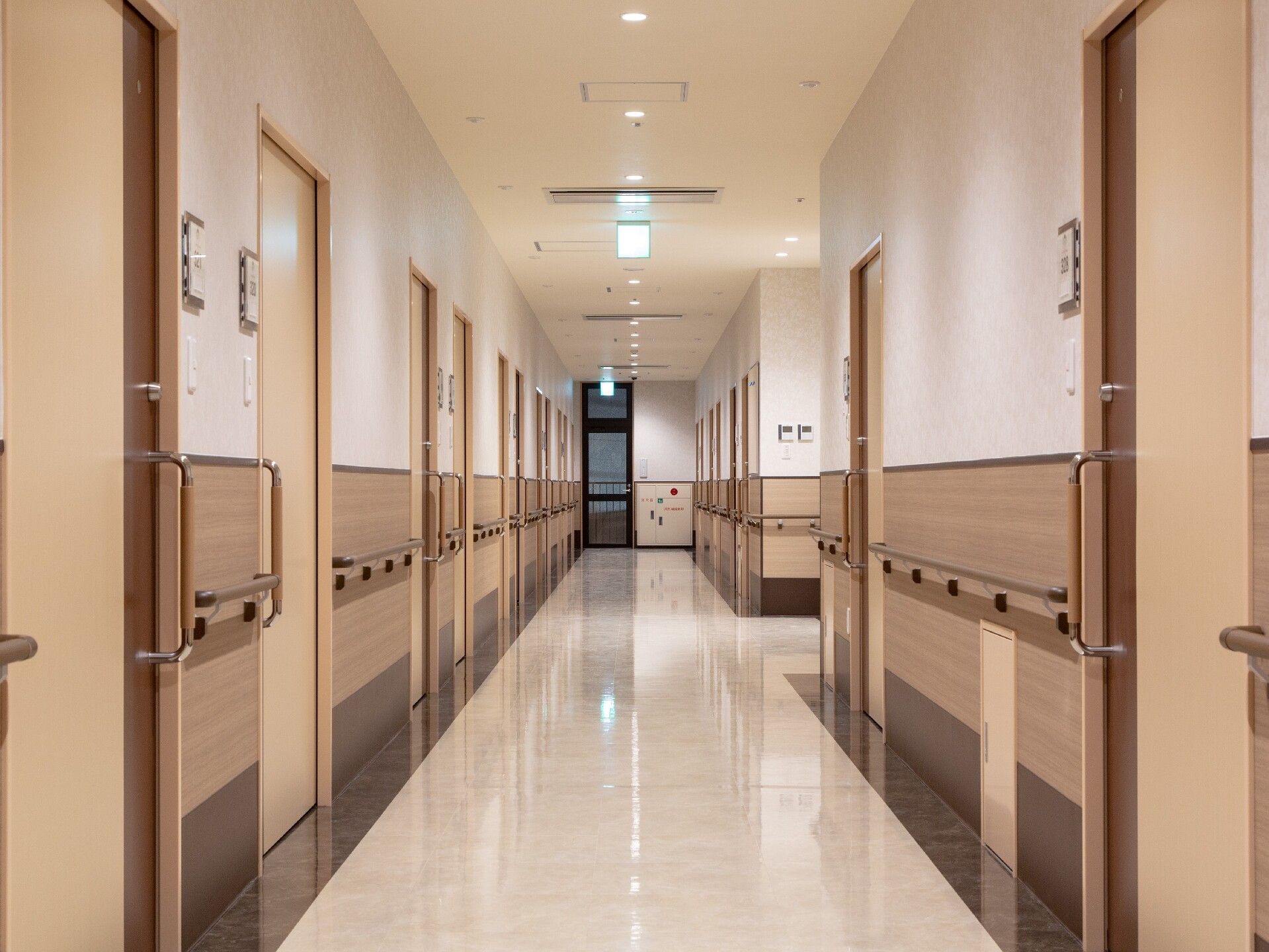 まっすぐな廊下には手すりが付き、両サイドに居室のドアが並んでいる。ドアのそばにはネームプレートのようなものがある。