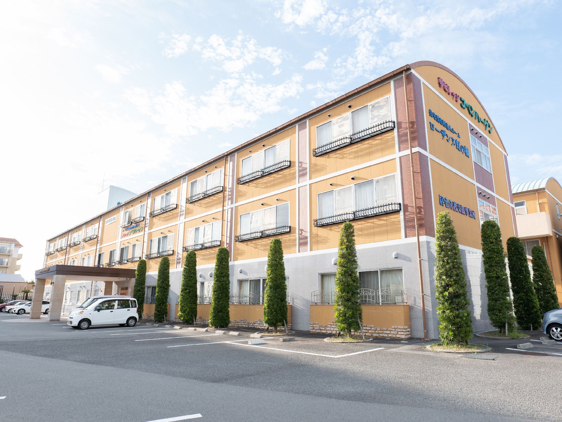 広い駐車場が隣接している、おしゃれな屋根のある介護施設