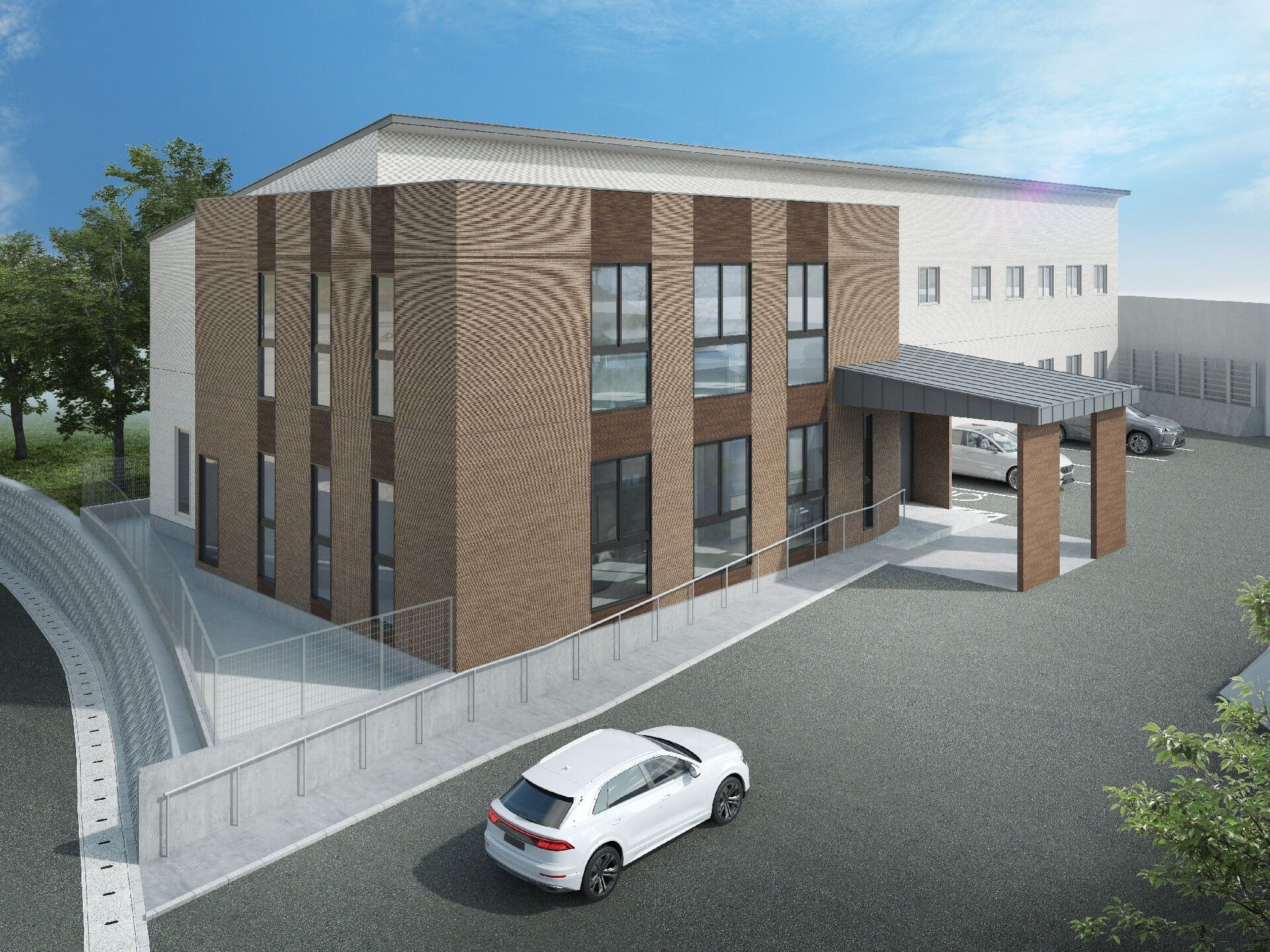 ブラウンと白の2階建ての建物の玄関には手すり付きのスロープがあり、建物の前には車が止まっている。
