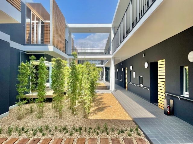 左右二つの建物を渡り廊下などで結んでいて、庭スペースもあり、外壁には手すりも付いている。