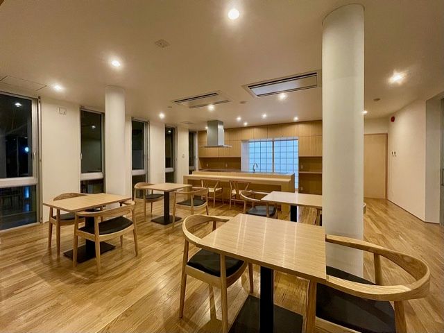 木製の二人用のテーブルセットが置かれている食堂の奥にはオープンタイプのキッチンがある。