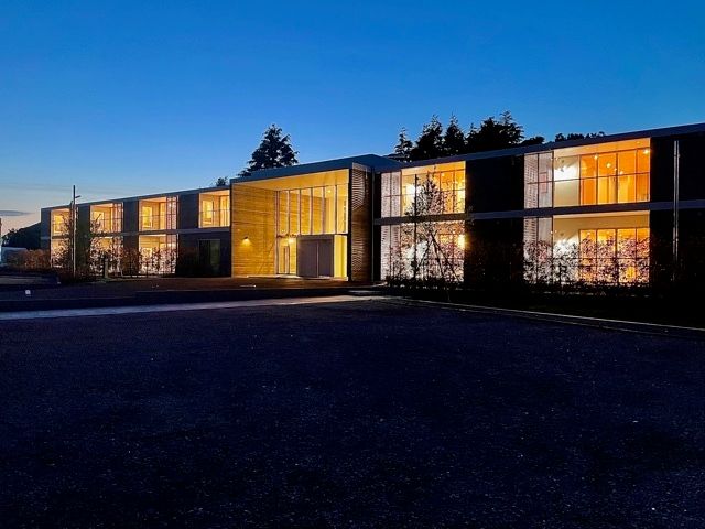 夕暮れ時になり明かりが灯っている建物全体のシルエットが浮かび上がっている。一面ガラス張りなので、とても明るい。