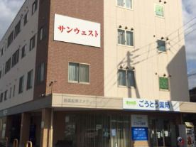 ブラウン系の外壁の４階建ての建物の玄関には車寄せが付き、日当たりのいい場所に建っている。