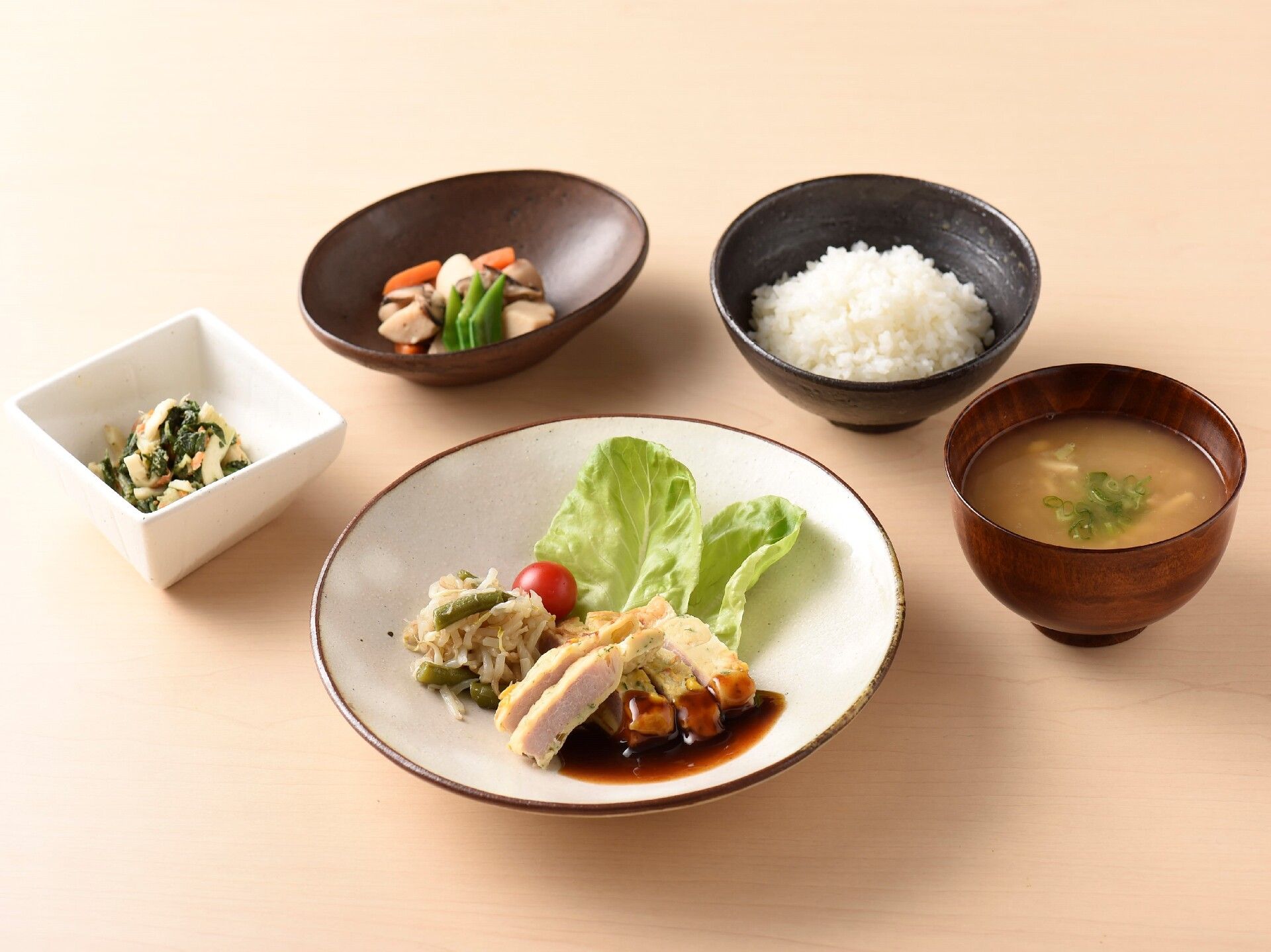 まる皿に鶏肉がメインの料理と小鉢に副菜が盛り付けられている