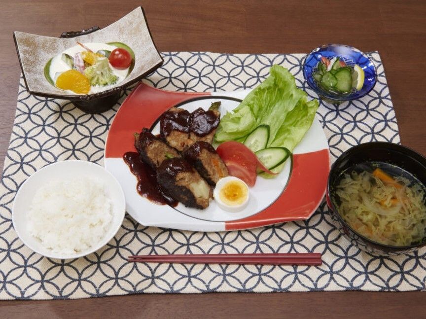 肉料理をメインとして、白いご飯や汁物、フルーツのヨーグルトあえ、野菜の小鉢などが並んでいる。