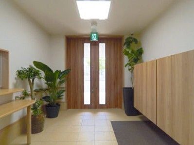観葉植物が複数置かれているエントランスには大きな靴箱があり、マットが敷かれ、受付もある。