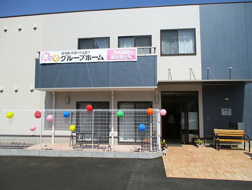 ２階建ての建物は玄関にベンチが置かれ、2階のベランダ部分にホーム名が書かれた幕が下がっている。