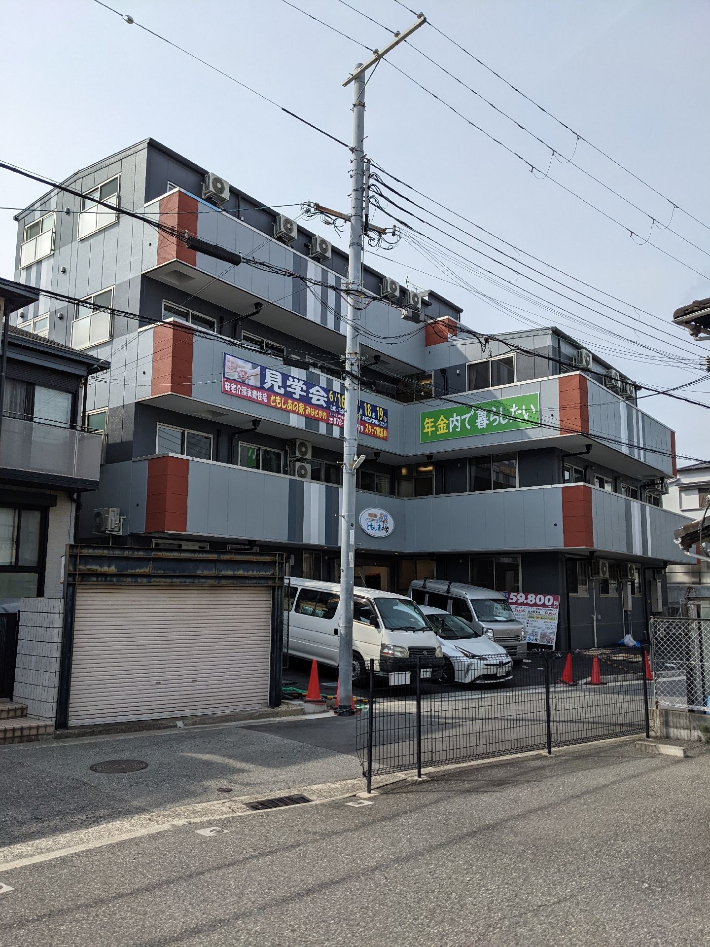眼鏡をかけた高齢男性が福祉車両から下りようとしている所を笑顔で介助している若いスタッフ。