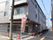 グレー系の外観の3階建ての建物で外壁にはホーム名が書かれ、玄関には瓦屋根が付いている。