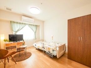 寝具付きのベッドが置かれている部屋にはエアコンやテレビ、テーブルセットが置かれている。