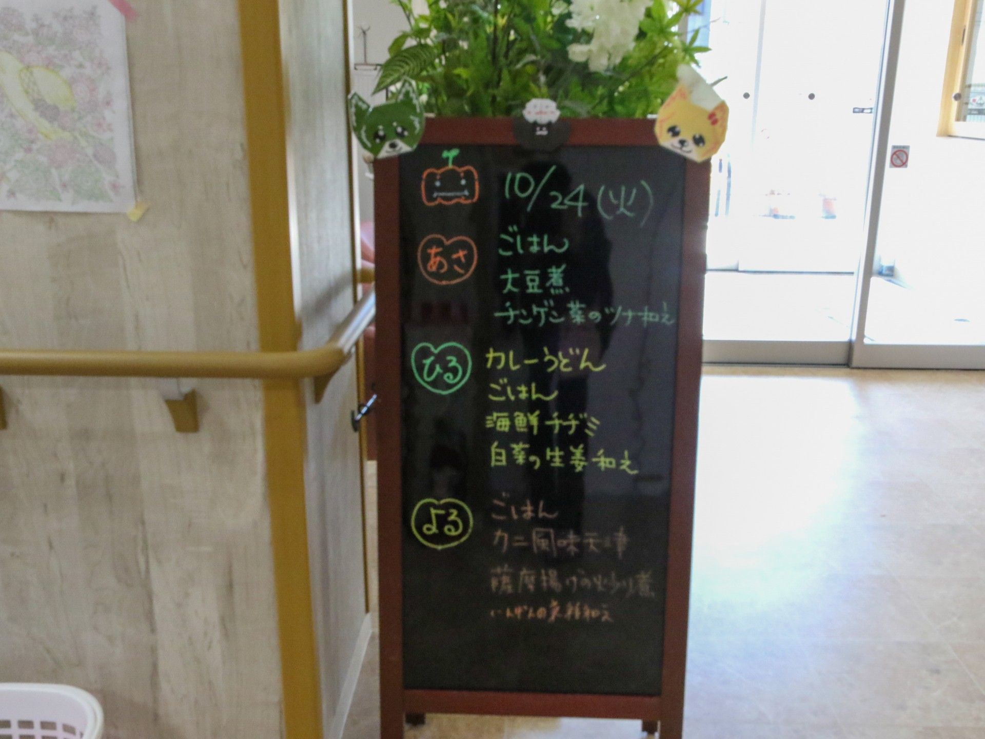 ボードにかかれたメニューに上には緑の植栽が飾られている