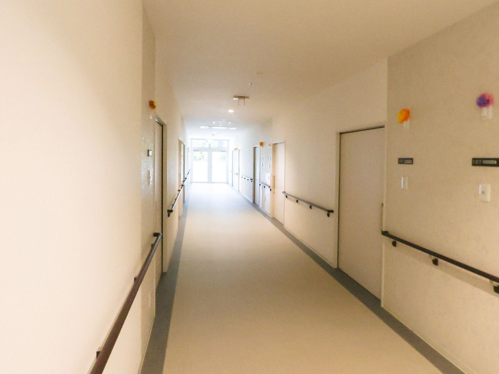 白い壁に茶色い手すりが設置されている廊下