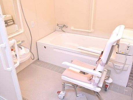 一人用の浴槽が設置された浴室。浴層にはリフトがあり、そばには車いすタイプのリフトがある。
