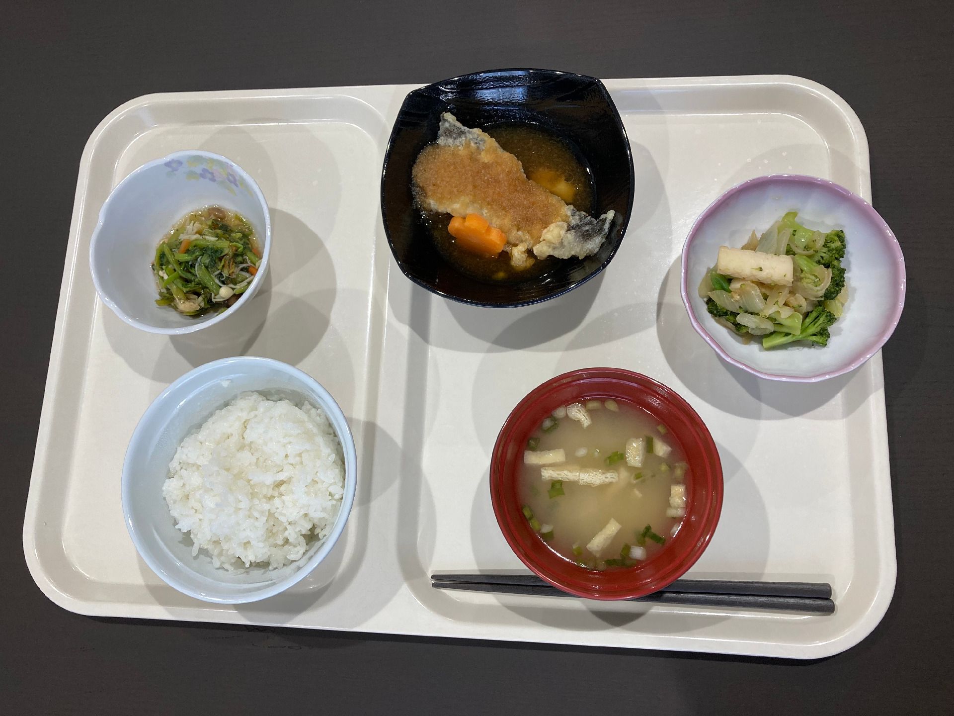 白いご飯に味噌汁、野菜の和え物や肉料理などが並んでいるトレーには箸も添えられている。