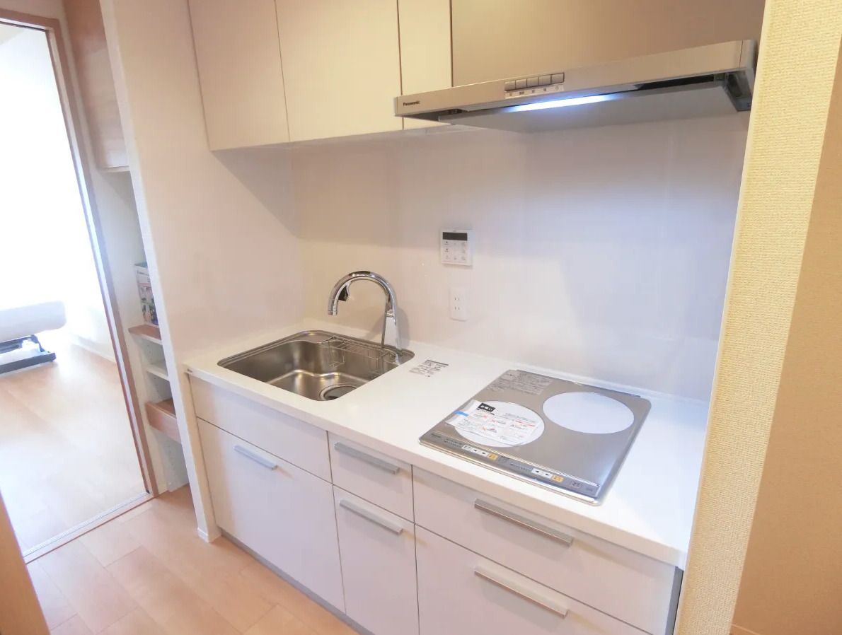 笑顔で屋外を散歩しているジャケットを着た高齢女性とエプロンを付けた女性スタッフ。