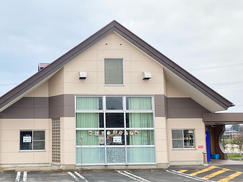 大きな窓が付いた平屋建ての建物には三角屋根が付き、敷地内には駐車場がある。