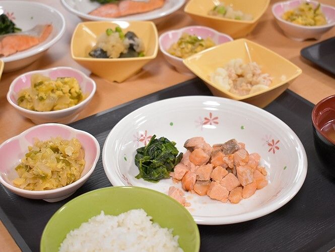 一口サイズにカットされた鮭やホウレン草がメインとなっていて、白いご飯や汁物、副菜などが盛られている。